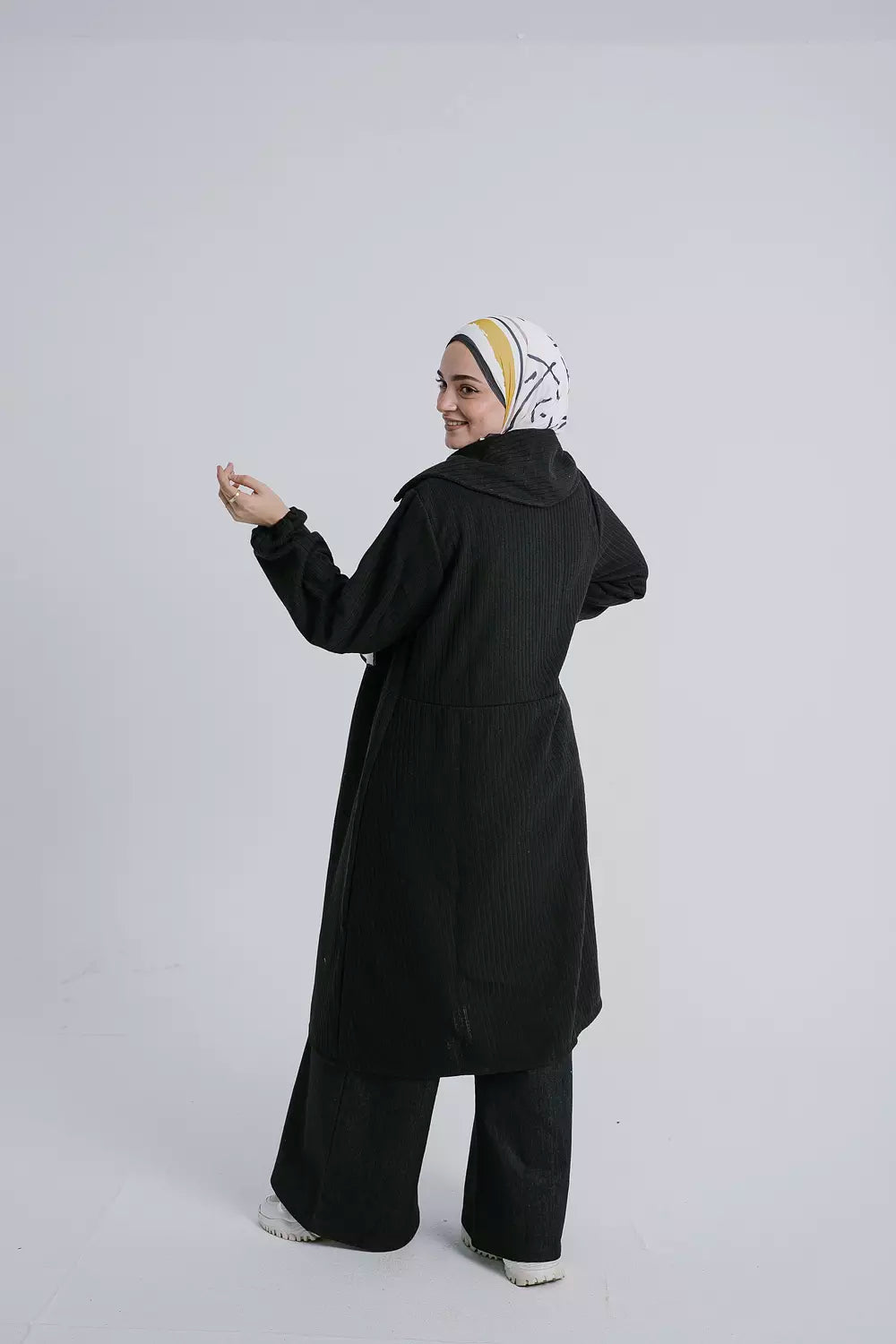 Back view of Enchanted Black Cardigan featuring the long sleeves and flowy fit. سترة باللون الأسود الداكن مع أكمام طويلة وقَصّة فضفاضة، منظر خلفي.