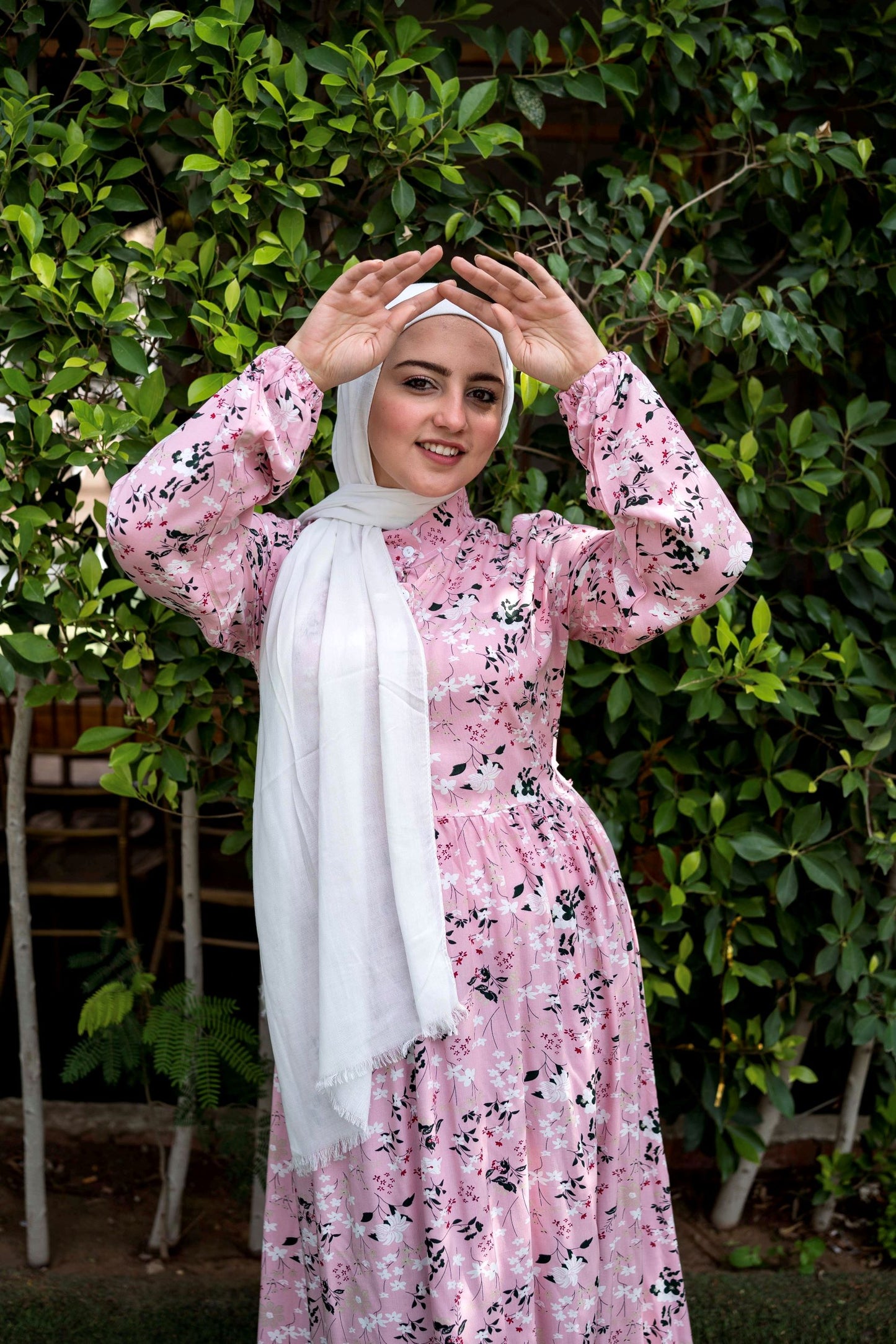 Model wearing Spring Dress in Pink, showcasing the floral pattern and long sleeves. عارضة ترتدي فستان ربيعي باللون الوردي بنمط زهور وأكمام طويلة