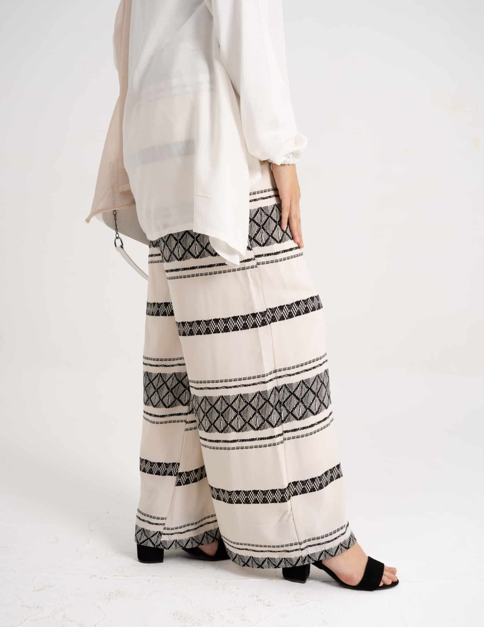 Side view of White Wide Pants showcasing the wide-leg cut. بنطلون واسع باللون الأبيض يظهر القَصّة الواسعة للساق، منظر جانبي.