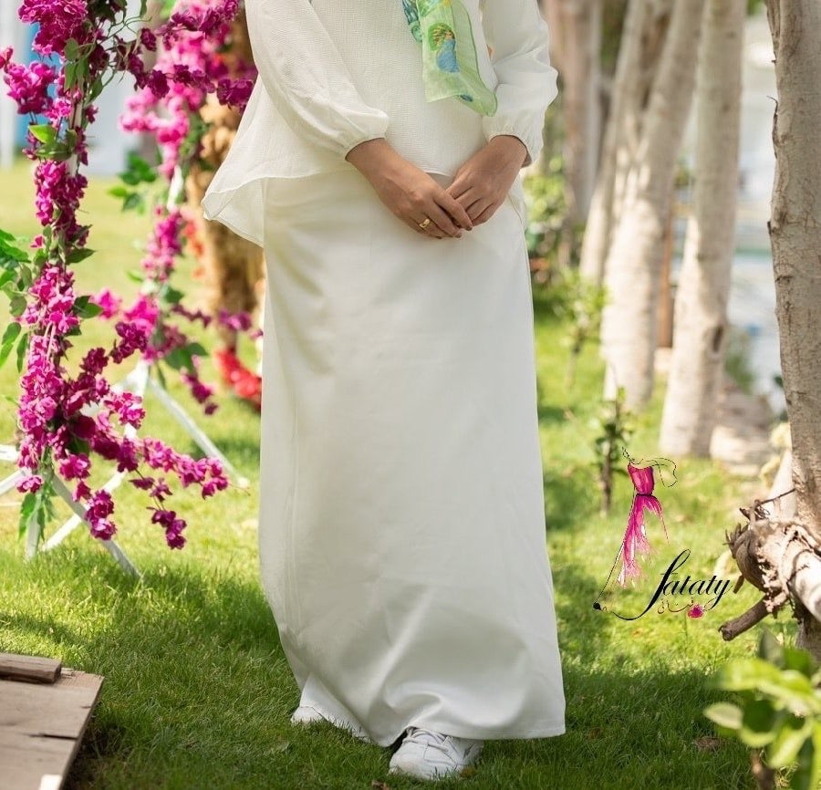 Front view of White Basic Skirt with a simple design and full-length cut. تنورة أساسية باللون الأبيض بتصميم بسيط وقَصّة بطول كامل، منظر أمامي.