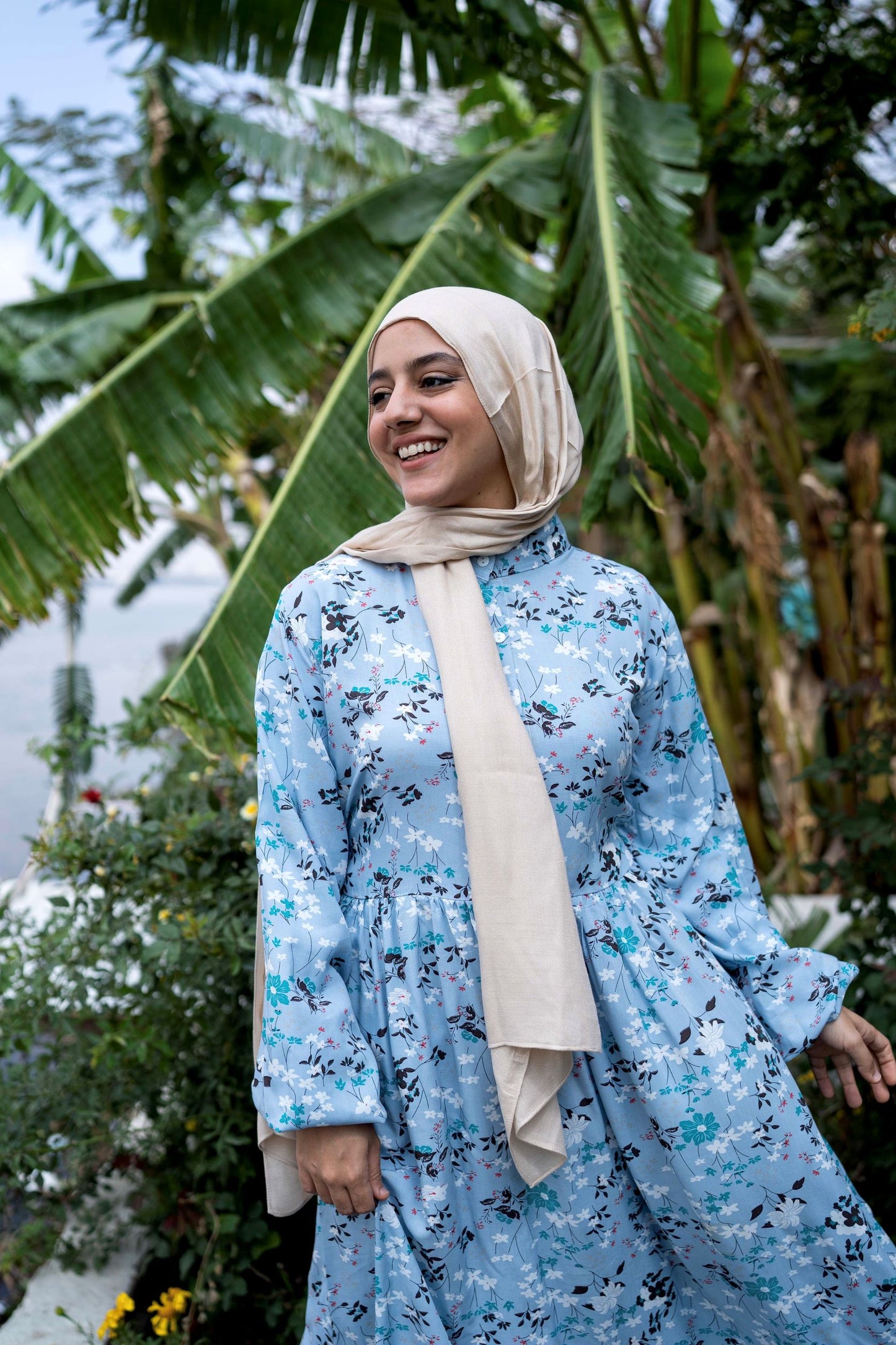 Model wearing Spring Dress in Blue, showcasing the floral pattern and long sleeves. عارضة ترتدي فستان ربيعي باللون الأزرق بنمط زهور وأكمام طويلة