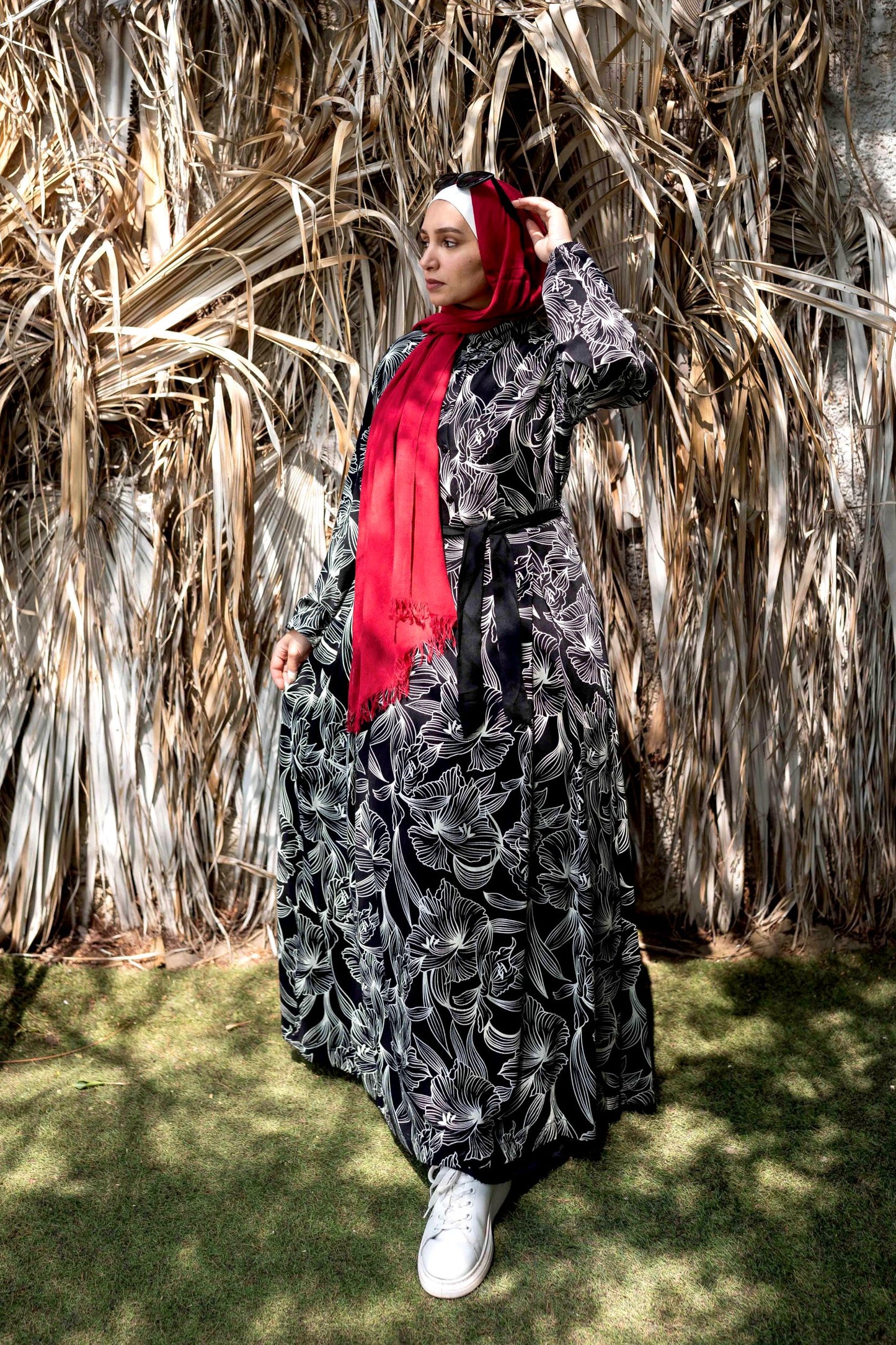 Front view of Floral Bloom Dress in Black with floral pattern and long sleeves. فستان بتلات الأزهار باللون الأسود بنمط زهور وأكمام طويلة، منظر أمامي.