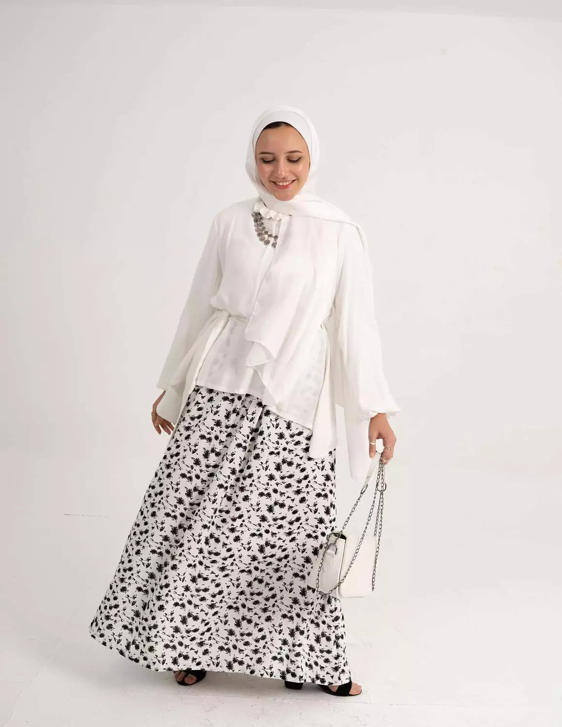 Model wearing White Flowy Skirt, perfect for an elegant and breezy look. عارضة ترتدي تنورة بيضاء انسيابية، مثالية لإطلالة أنيقة ومنعشة.