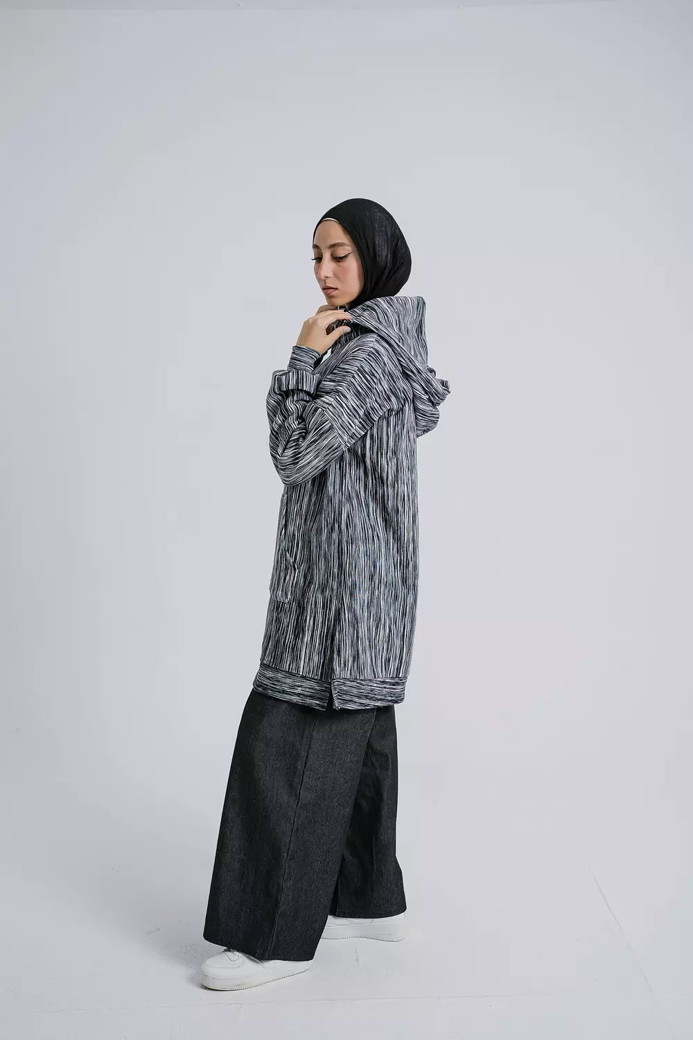 Side view of Dark Elegance Hoodie showcasing the hood and sleek design. سويت شيرت باللون الأسود الداكن يظهر غطاء الرأس والتصميم الأنيق، منظر جانبي.