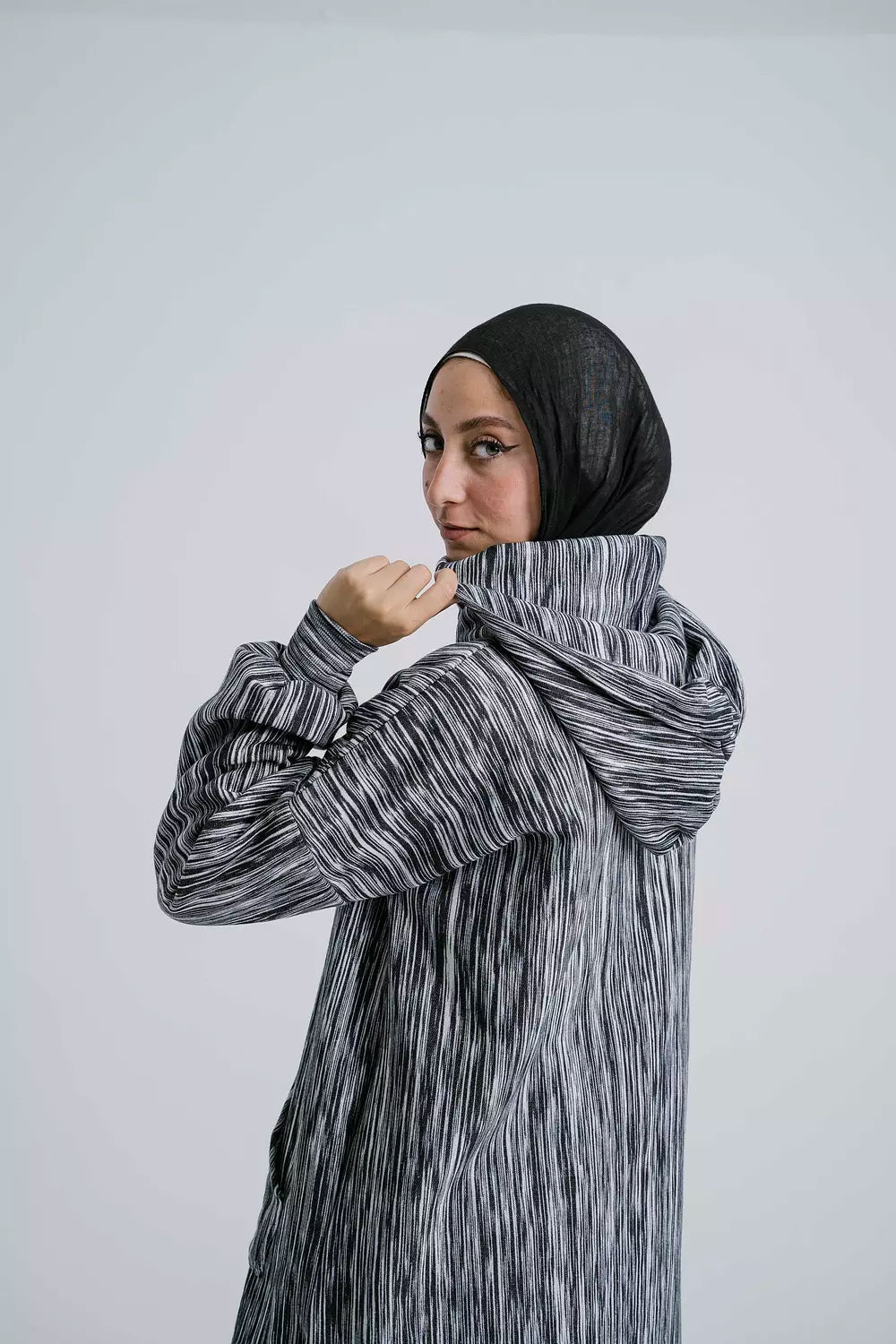 Side view of Dark Elegance Hoodie showcasing the hood and sleek design. سويت شيرت باللون الأسود الداكن يظهر غطاء الرأس والتصميم الأنيق، منظر جانبي.