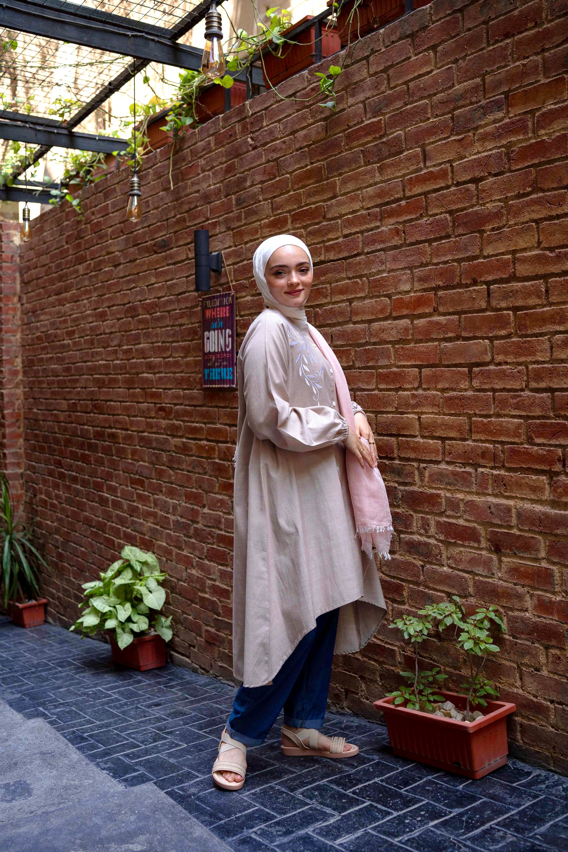 Side view of Long Shirt in Beige showcasing the long sleeves and relaxed fit. قميص طويل باللون البيج يظهر الأكمام الطويلة والتصميم المريح، منظر جانبي.