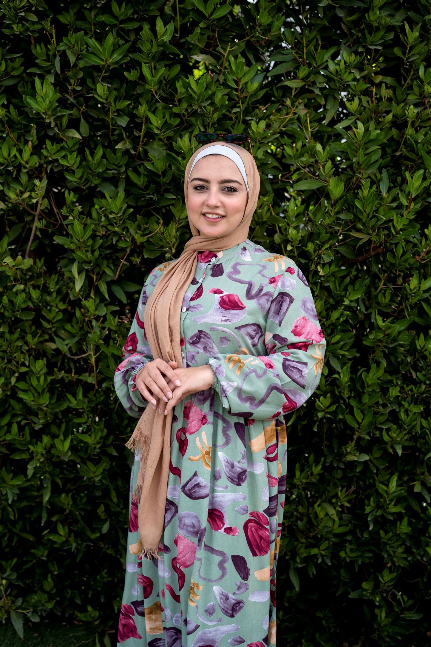 Model wearing Sea Stones Dress in Green, showcasing the sea-inspired pattern and long sleeves. عارضة ترتدي فستان بأحجار البحر باللون الأخضر مع نمط مستوحى من البحر وأكمام طويلة.