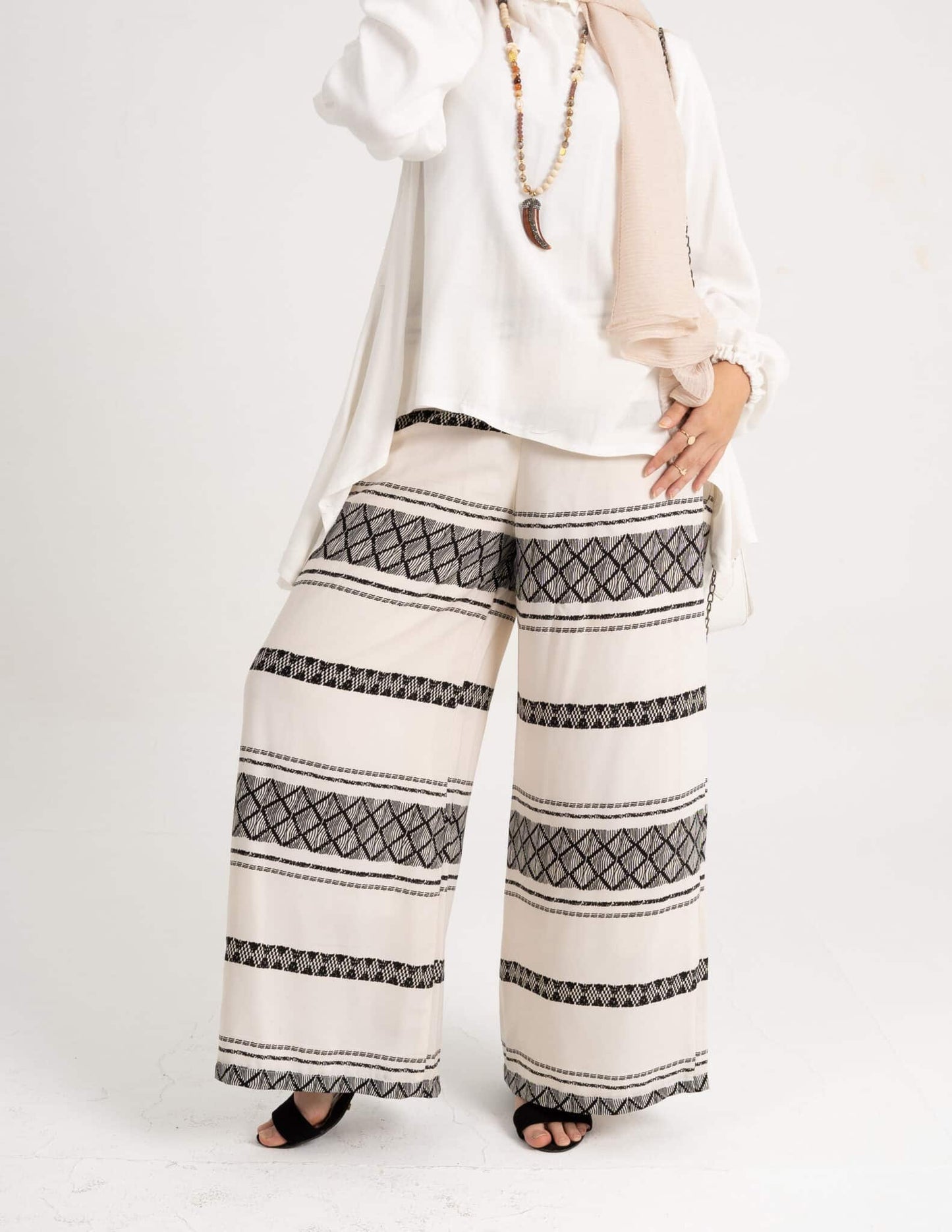 Front view of White Wide Pants featuring a classic design and wide-leg cut. بنطلون واسع باللون الأبيض مع تصميم كلاسيكي وقَصّة ساق واسعة، منظر أمامي.