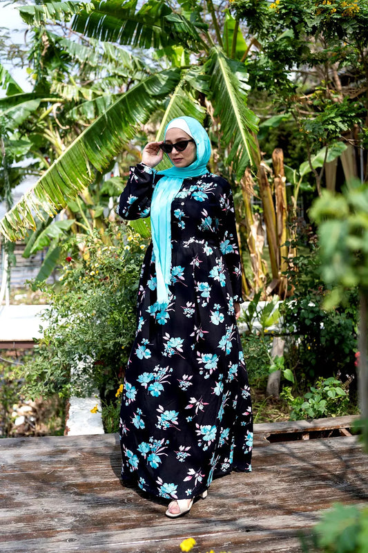 Front view of Turquoise Daisy Dress with daisy print and long sleeves. فستان تركوازي بنمط زهور الأقحوان وأكمام طويلة، منظر أمامي.